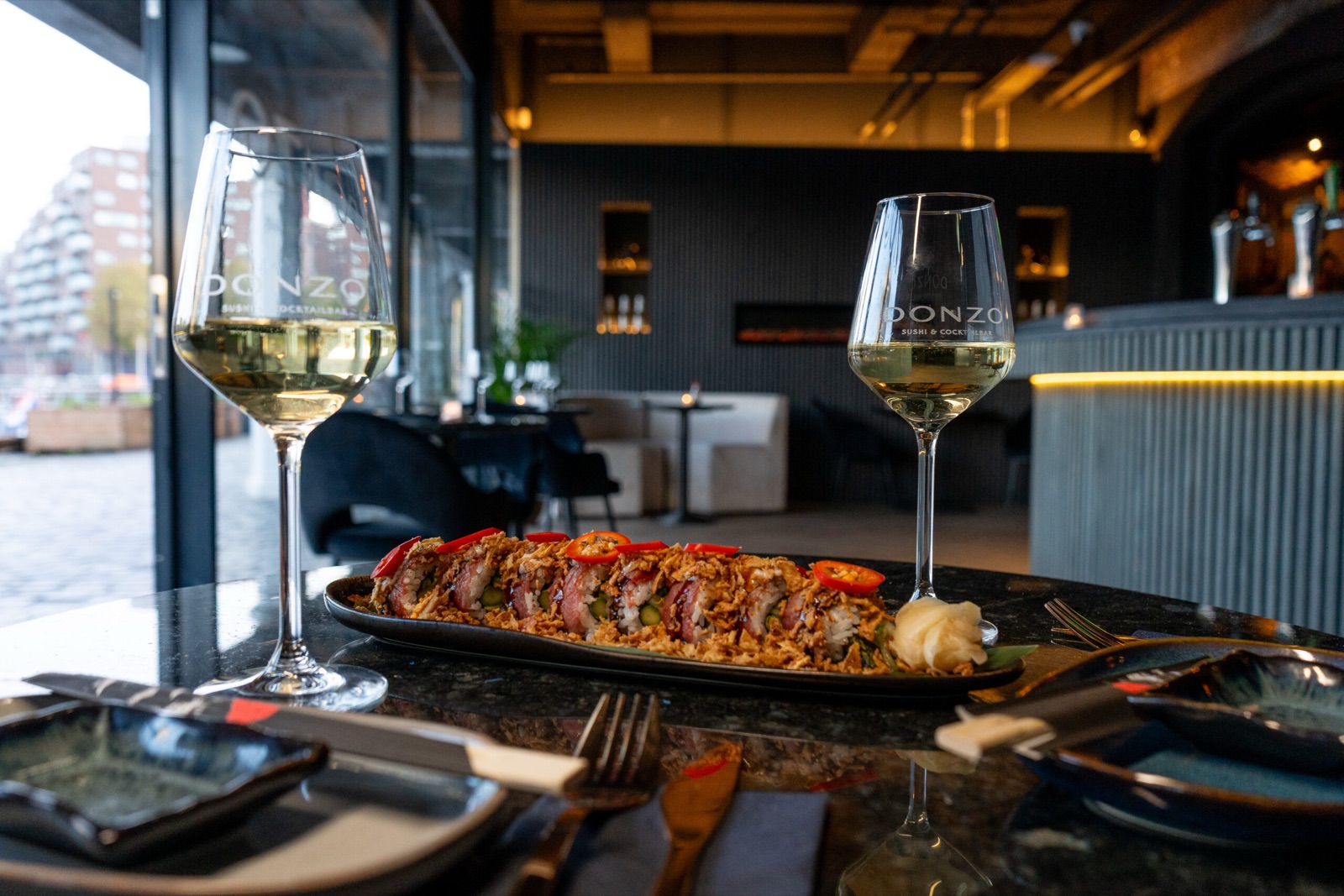 Sushi and Donzo branded wine glasses with Rotterdam city view Kop van Zuid